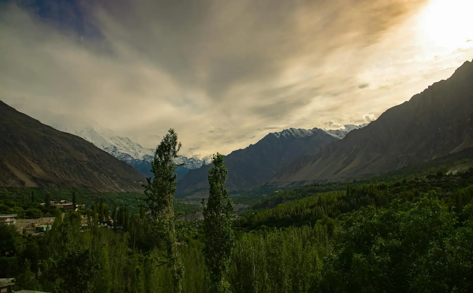 Breathtaking view of Hunza Valley at sunset with lush greenery and majestic mountains
