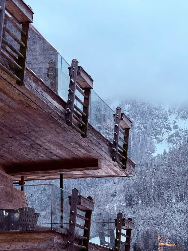 A rustic wooden balcony of a lodge against snowy alpine mountains